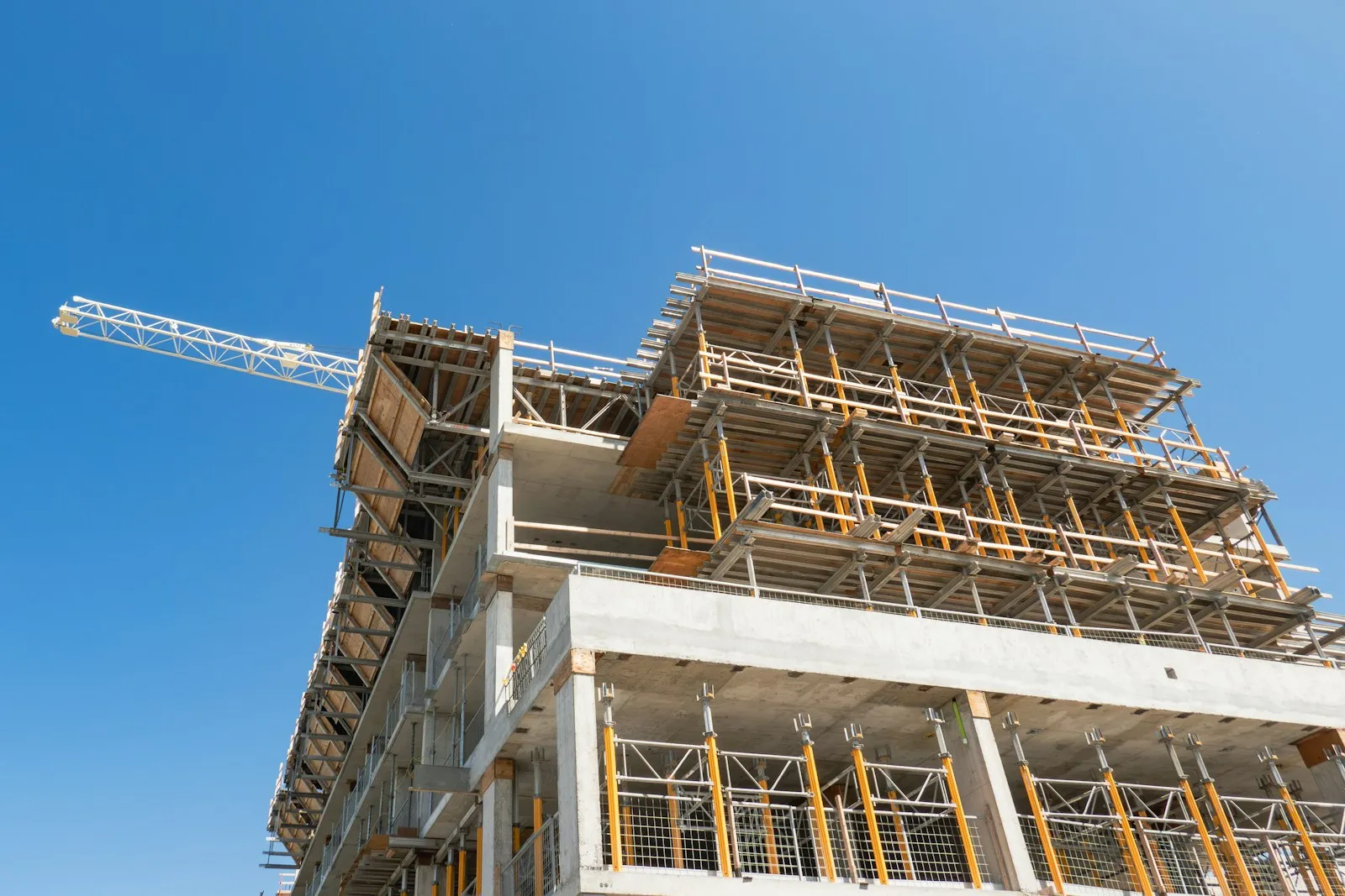 Concrete high-rise under construction with a tower crane and scaffolding